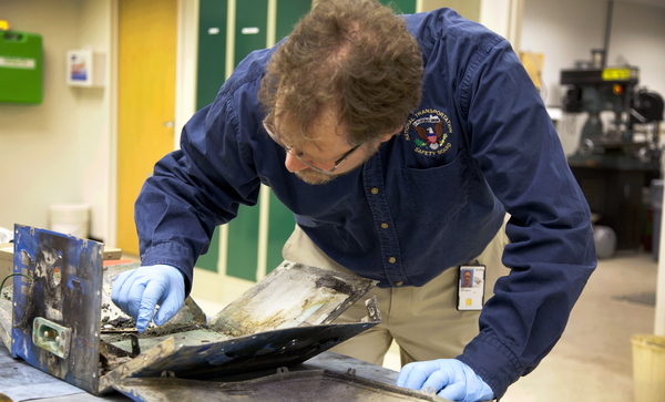 L'ingénieur en matériaux du NTSB Matt Fox examine le boîtier de la batterie impliqué dans l'incident JAL Boeing 787 à Boston